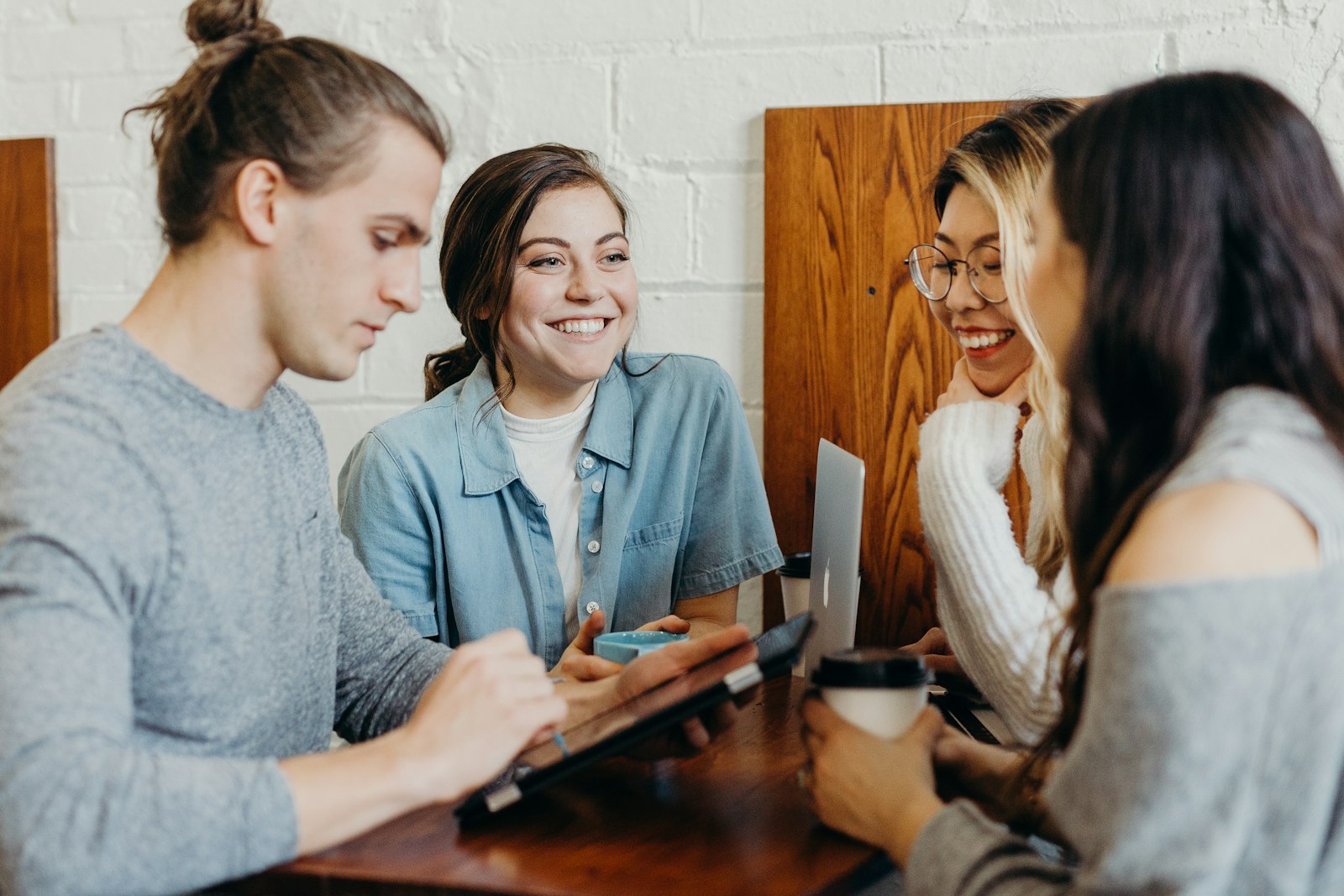 Two friends sitting at a table in conversation, one listening closely to the other.